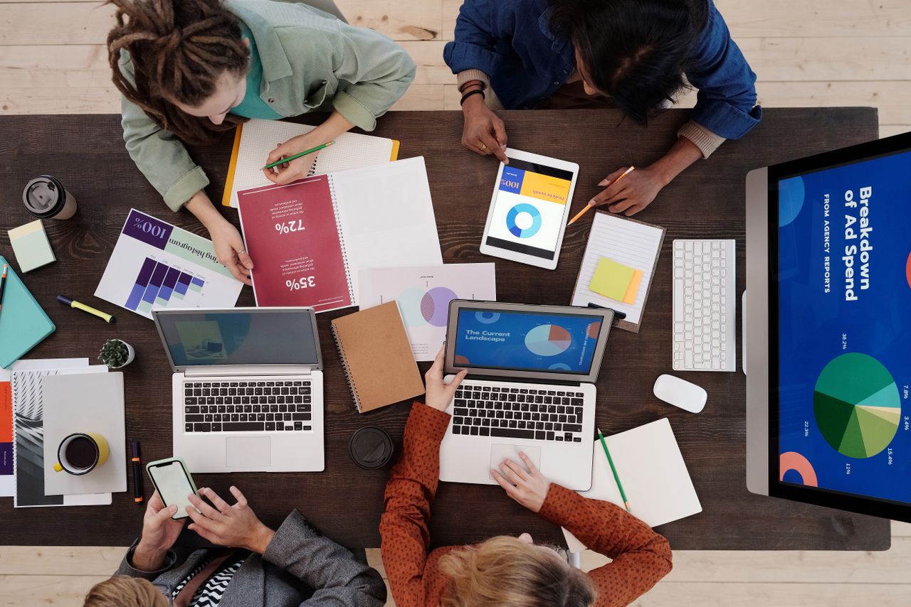 why-choose-us A diverse team collaborating on digital marketing strategies at a desk, using laptops and tablets.